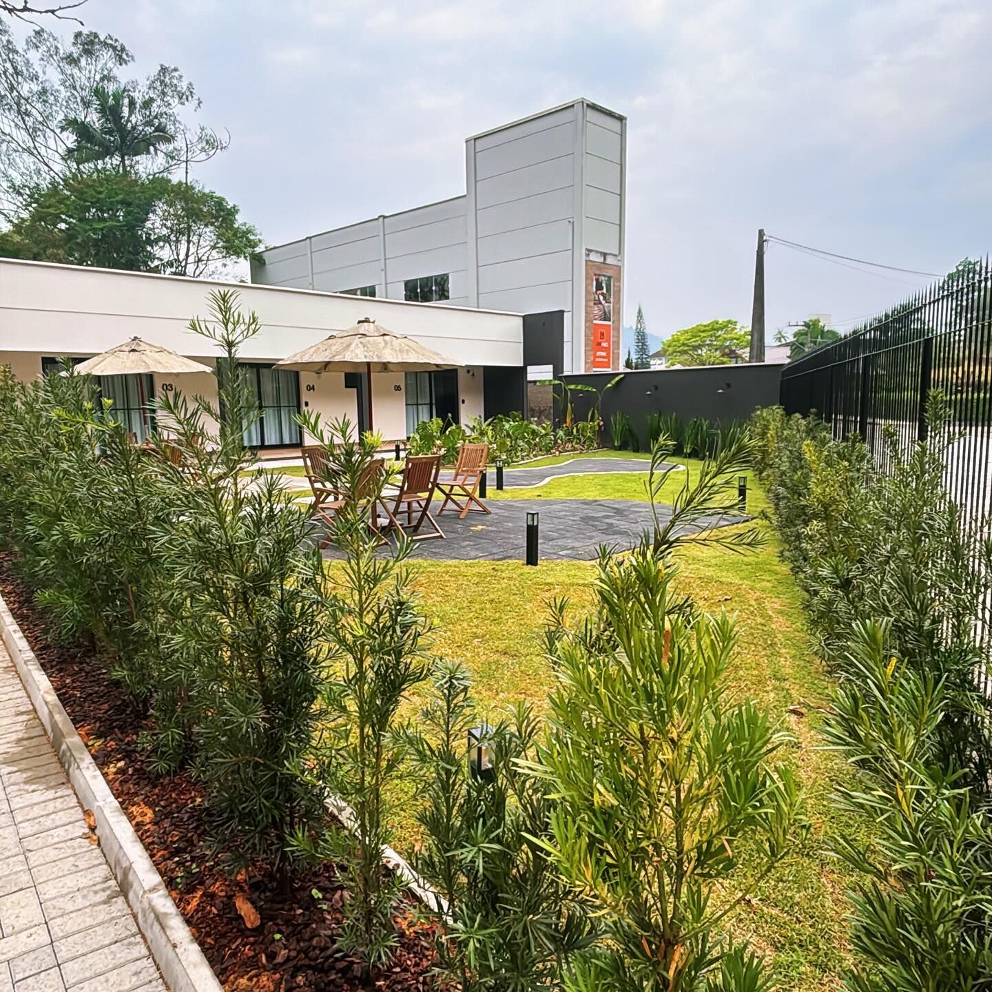 Jardim da Pommerlofts durante o dia, com mesas, gramado e árvores